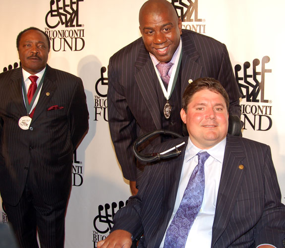 Former NBA point guard Earvin Johnson poses with Marc Buoniconti as Hall of Fame second baseman Joe Morgan looks on in the background.